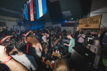 The DJ stands under a "Please Order Here" sign.