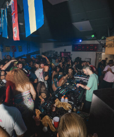 The DJ stands under a "Please Order Here" sign.